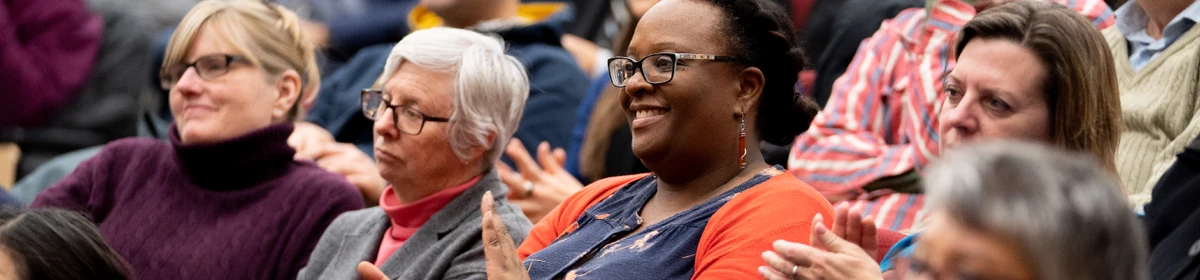 A photo of a crowd of AMAPCEO members smiling and clapping