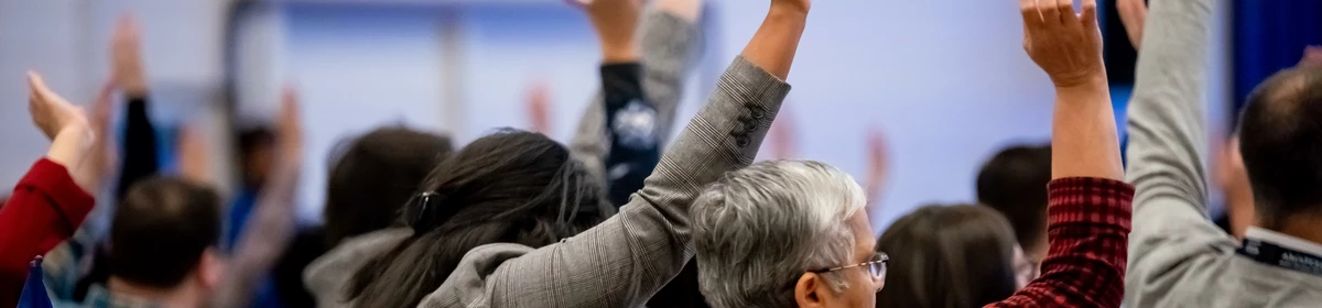 A group of AMAPCEO Delegates raising their hand to vote 