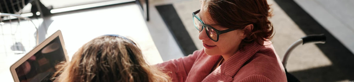 Two people looking at a laptop and talking