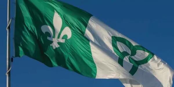 A Franco-Ontarian flag waving against a blue sky