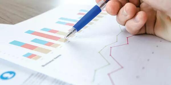 A hand with a pen reviewing some statistics