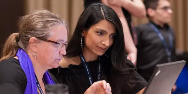 An AMAPCEO Workplace Representative is helping a fellow member. They are both sitting at a laptop.