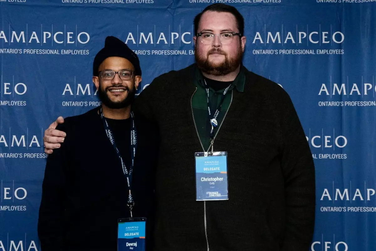 Chris Cully and Devraj Ray in front of AMAPCEO banner