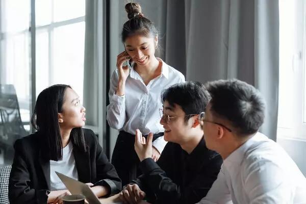 Group of people gathered in front of a laptop in an office 
