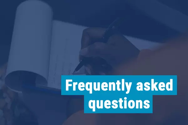 A person writing on a notepad "Frequently asked questions"
