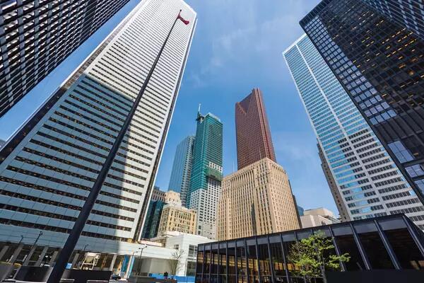 A low-angle photo of financial towers in downtown Toronto against a blue sky