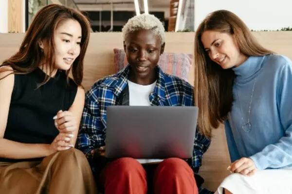 Three people gathered around a laptop