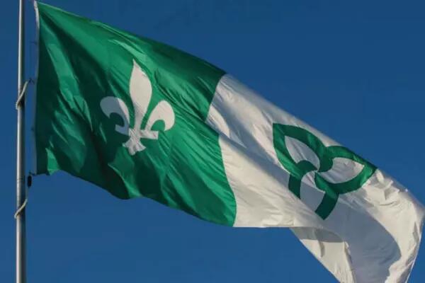 A Franco-Ontarian flag waving against a blue sky