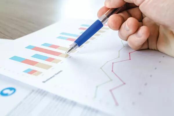 A hand with a pen reviewing some statistics