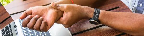 image of someone holding their wrist in front of their laptop