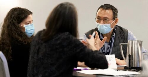 Members talking at a table wearing masks 