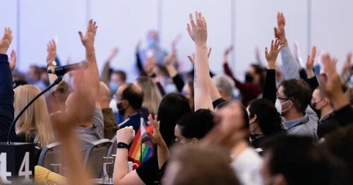A group of AMAPCEO Delegates raising their hand to vote 