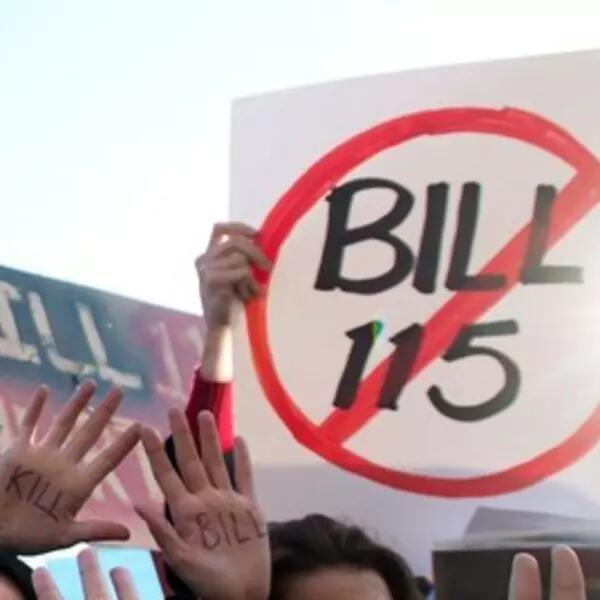 A sign with "Bill 115" in the centre of a red circle with a line through it