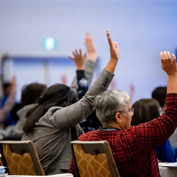 A group of AMAPCEO Delegates raising their hand to vote 