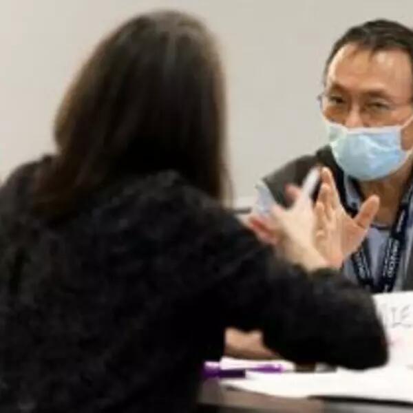 three people sitting around a table having a discussion