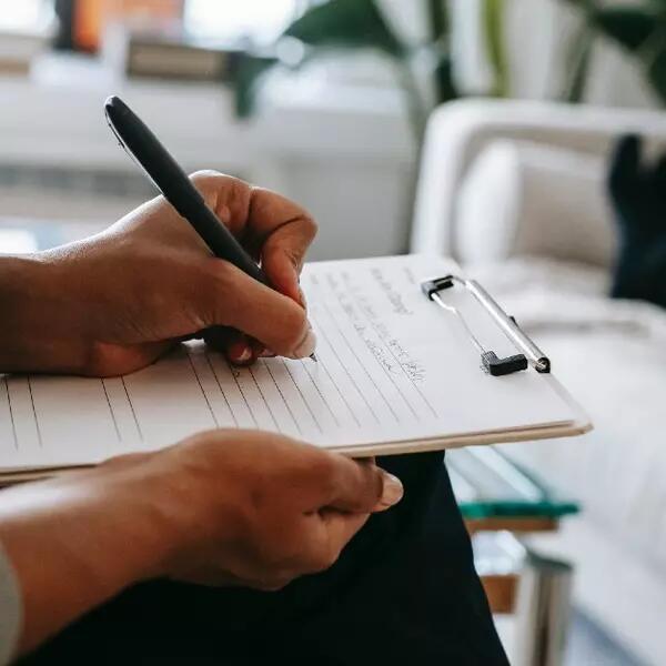 Photo of a hands holding a checklist with a person reclining in the background