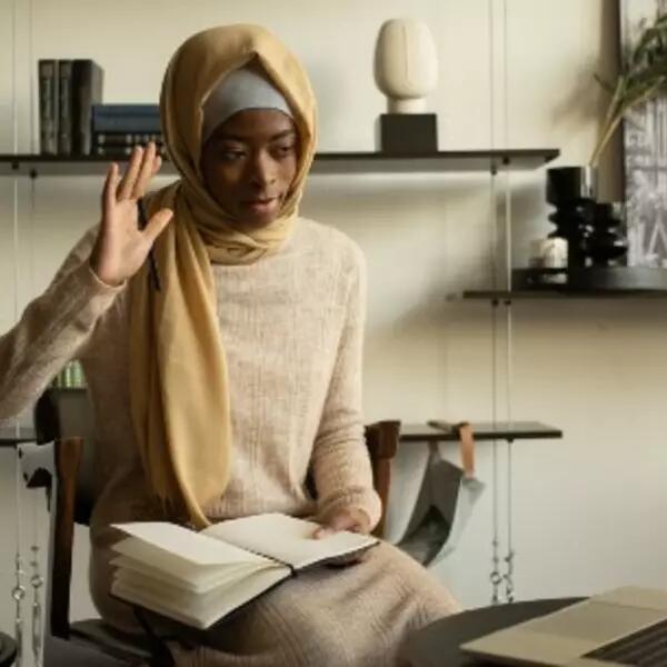 image of person in front of a laptop raising their hand